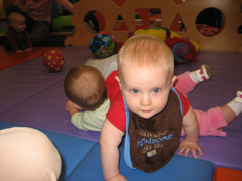 William crawling over someone at Gymboree